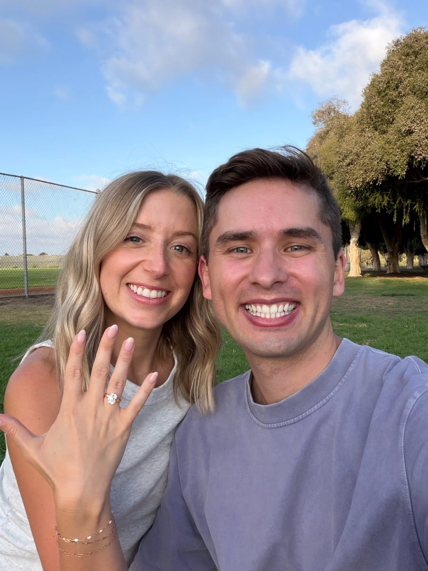 Camille and Zach smiling into the camera, the ring on show